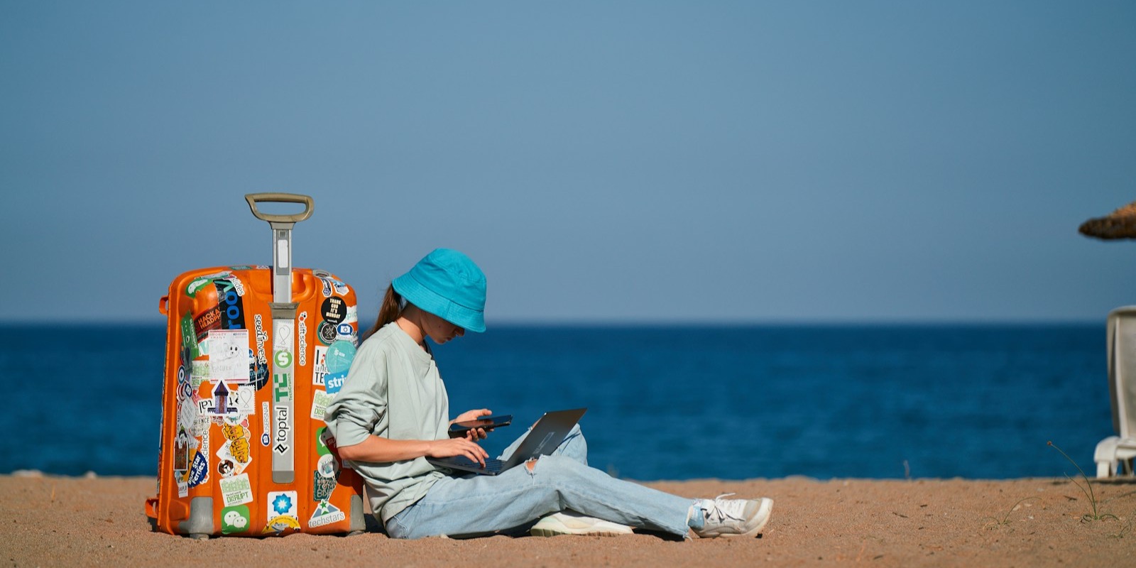 A traveller working on a laptop by the sea