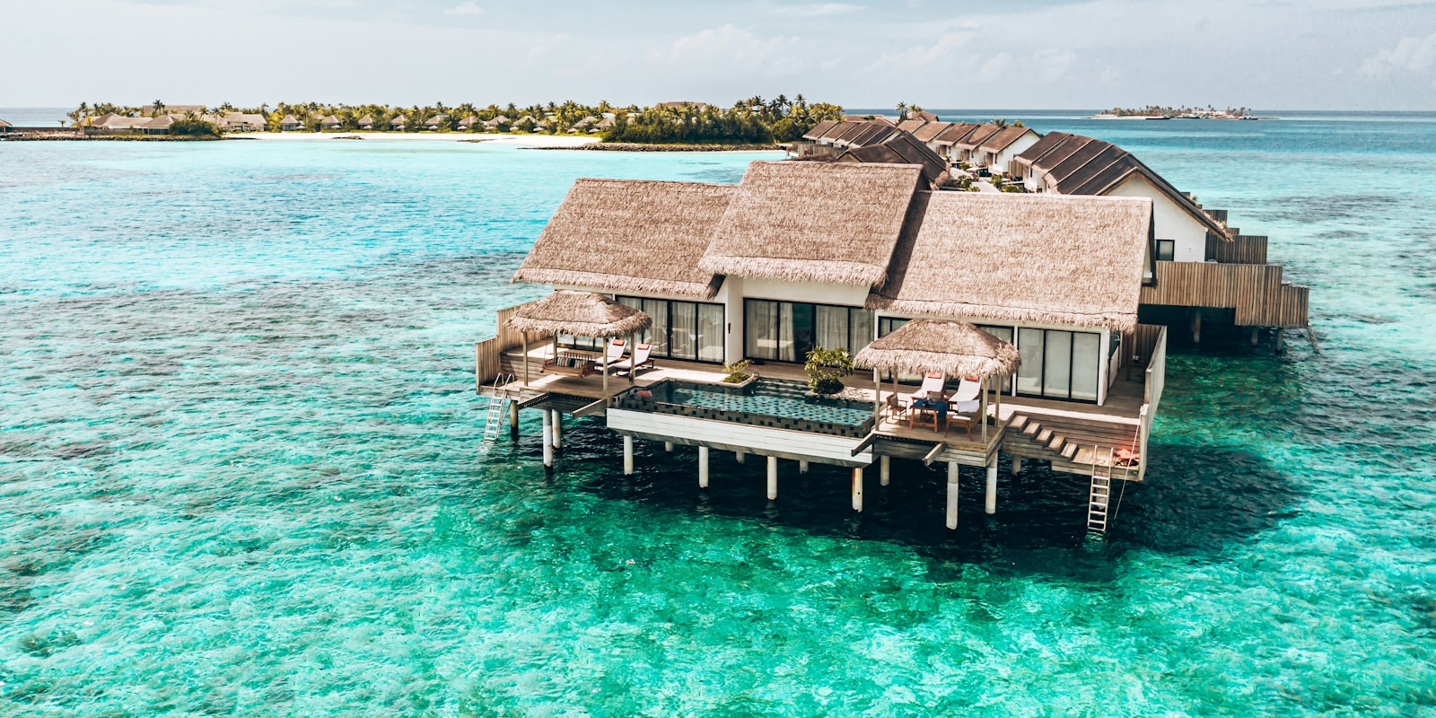 Overwater villas stretching into a turquoise Maldivian lagoon at midday