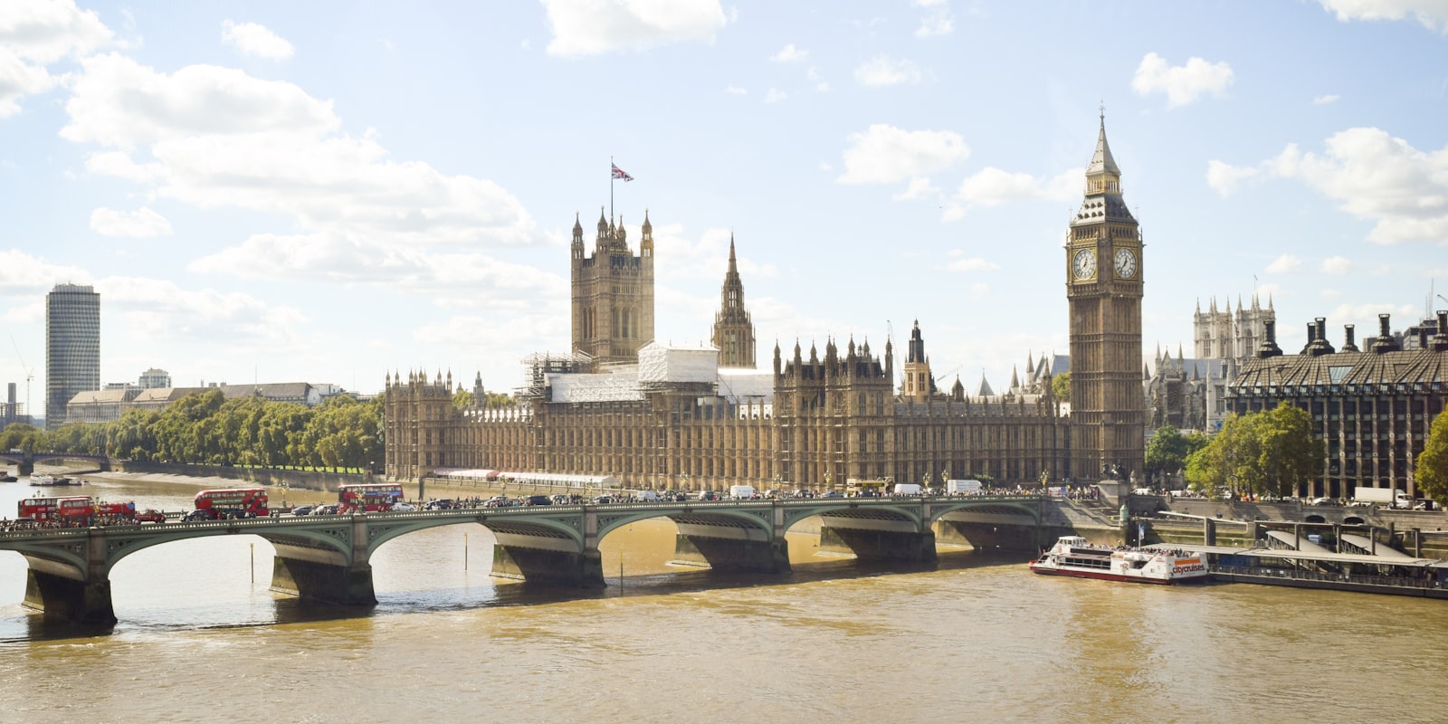 Westminster and the Thames at dusk with red buses crossing the bridge